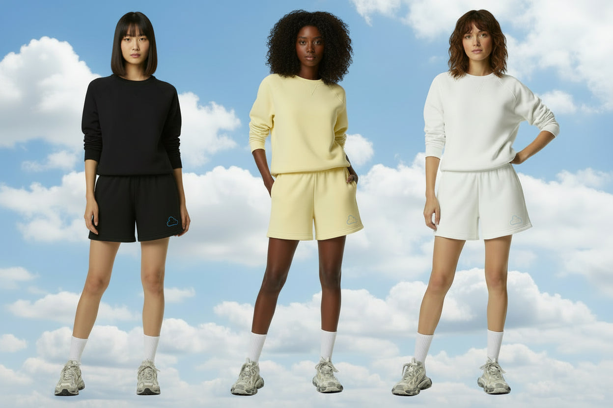 Three women wearing different colored outfits against a blue sky with clouds background